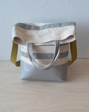 Load image into Gallery viewer, The top folds down to create a flap that conceals a generous zippered pocket. (showing the iridescent silver handle version).